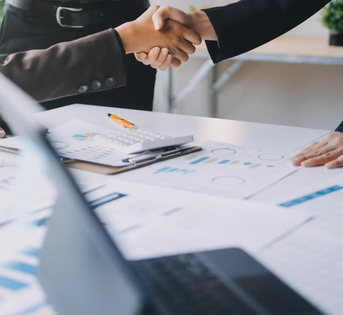 Business partners shaking hands over documents