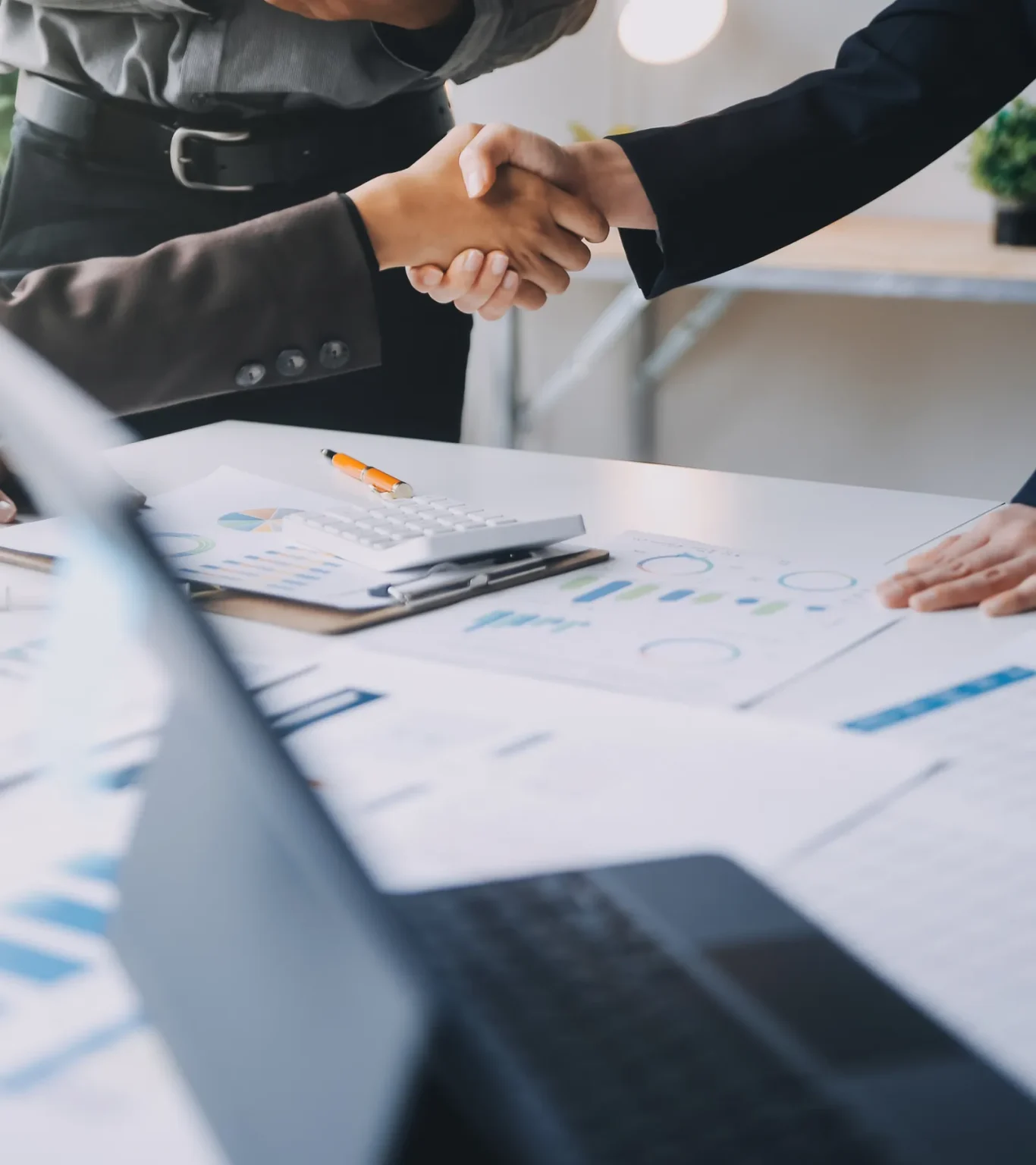 Business partners shaking hands over documents